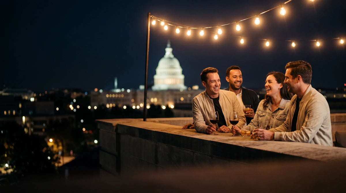 Friends talking over drinks on a rooftop at night with string lights and the city behind them